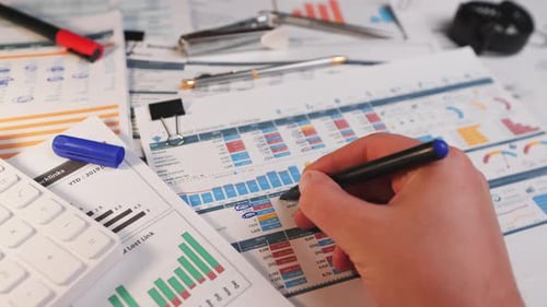 Analyst Circling Financial Data on Charts and Graphs