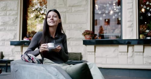 Young Woman Enjoying Coffee on Street