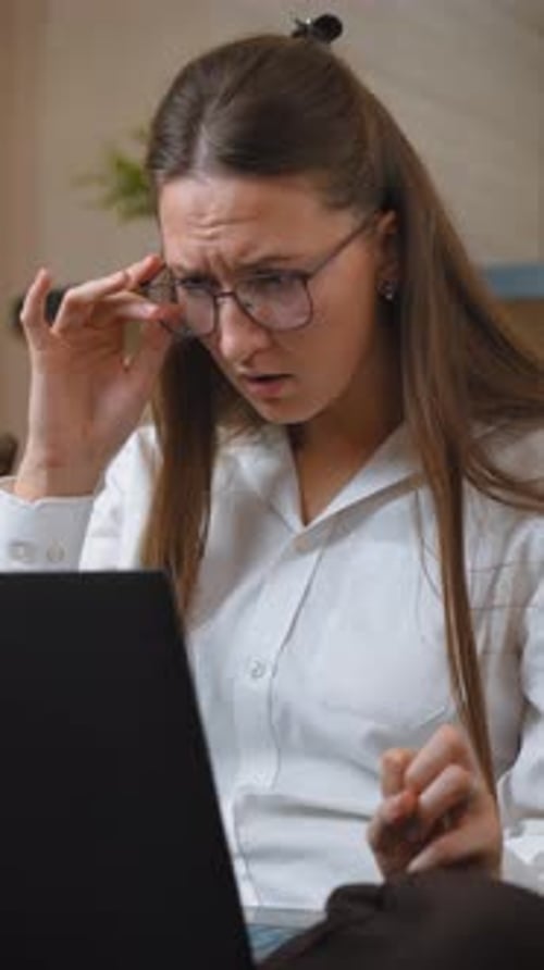Geschäftsfrau passt die Brille an und reagiert schockiert auf den Laptop-Bildschirm
