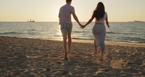 Young Loving Couple Have Fun Running on the Beach at Sunset