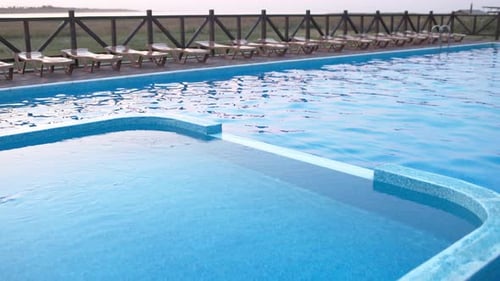 Blick von oben auf den Swimmingpool mit klarem Wasser im Urlaub auf Sonnenuntergang-Hintergrund