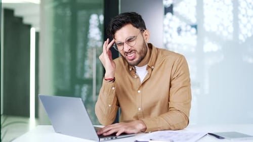 Young Man Working on Computer Gets Headache