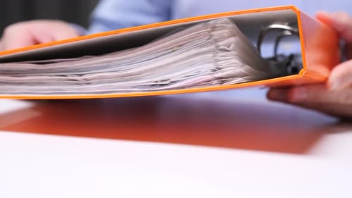 Closeup Office Worker Browsing Through Documents in Orange Binder