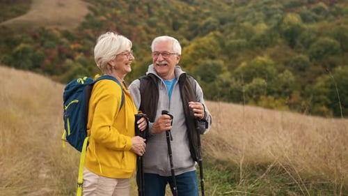 Smiling Senior Couple Hiking on Grassy Hill