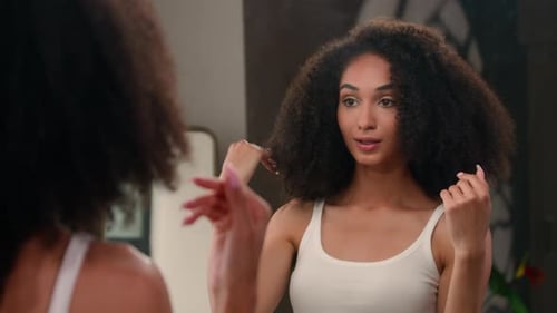 Woman Styles Her Afro Textured Hair In Mirror