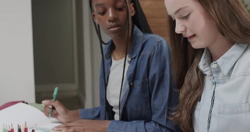 Des amies adolescentes concentrées et diversifiées qui étudient et discutent à table