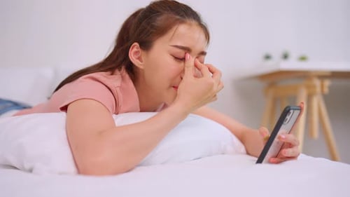 Woman Lying on Bed, Looking at Phone