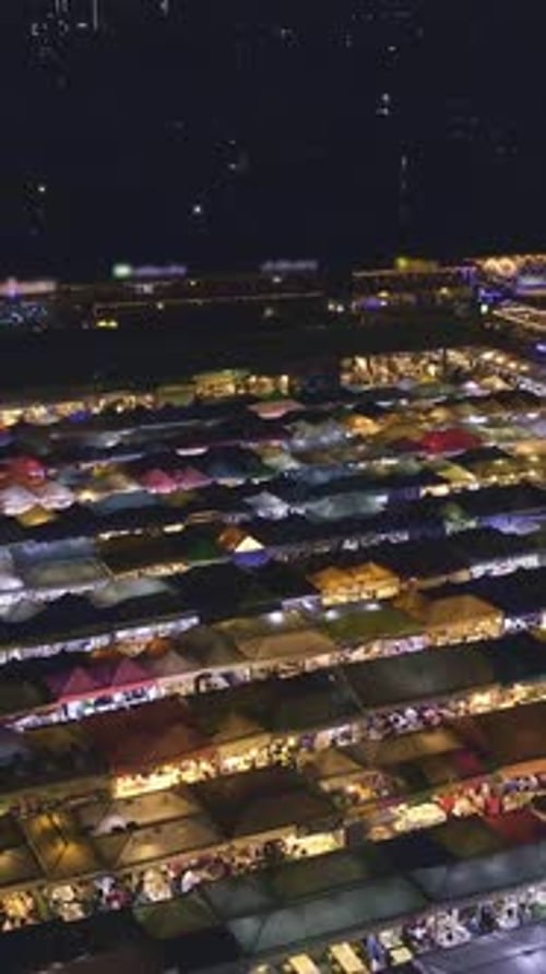 Panning Over Rows of Colorful Market Tents and Food Stalls at Night