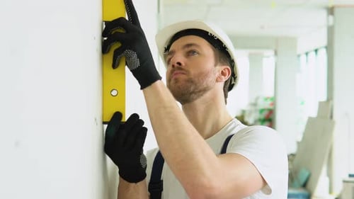 Construction Worker Checks Level on Wall Indoors