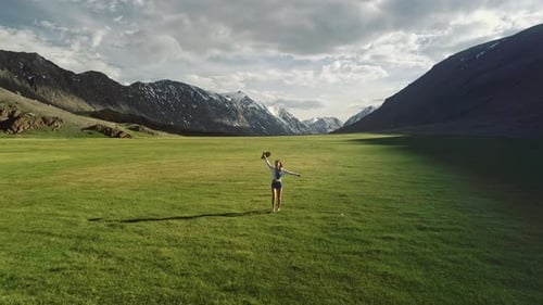 Happy Young Girl is Skipping Across the Field Mountains and Sky are in the Background The Concept of