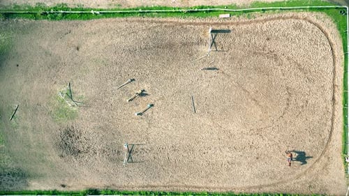 Aerial view of three horsemen. A riding field with fence and obstacles to train horses. In this spor