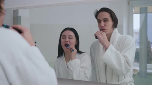 Mirror Reflection Portrait of Joyful Young Couple Having Fun Brushing Teeth in the Morning Cheerful