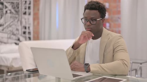 Young Adult Working on Laptop at Glass Desk