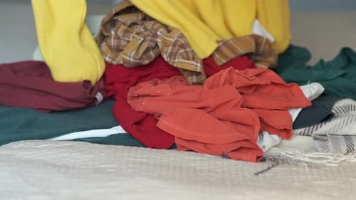 Sorting Through Colorful Pile of Clothes on Bed