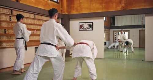 Young Adults Practice Judo in Dojo