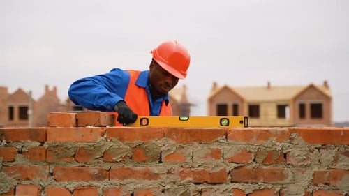 Construction Worker Leveling Brick Wall at Cottage Building Site