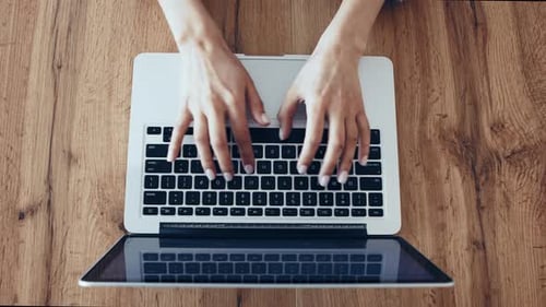 Woman Typing on Laptop Keyboard on Wood Surface