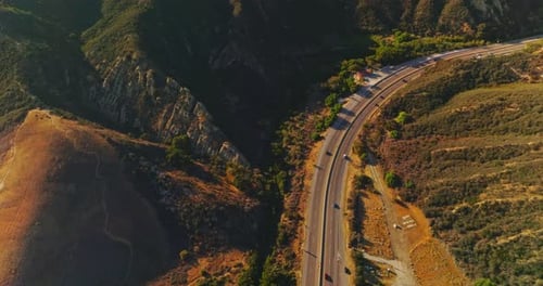 Autoroute dans la localité montagneuse par beau temps ensoleillé. Drone descendant au-dessus de la route