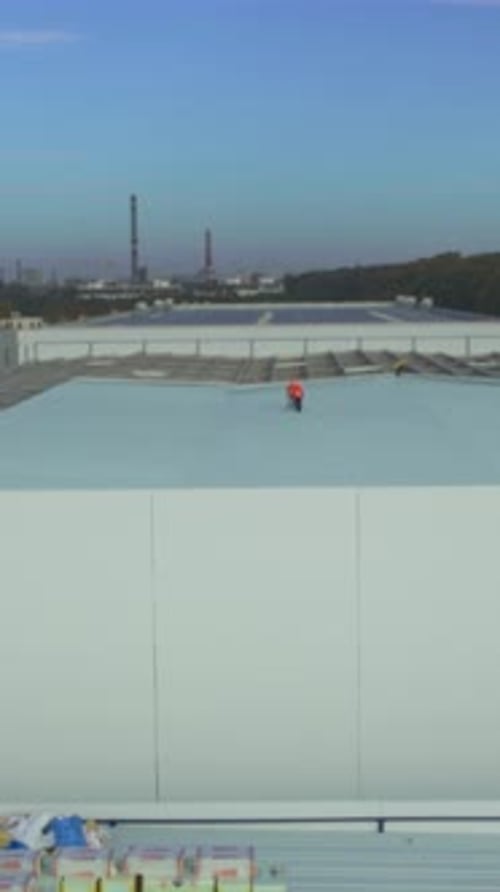 Workers Installing Insulation Panels High Above Safety Gear Worn During Rooftop Insulation