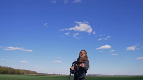 Beautiful young singer dancing with a microphone on a field. Pretty female soloist singing