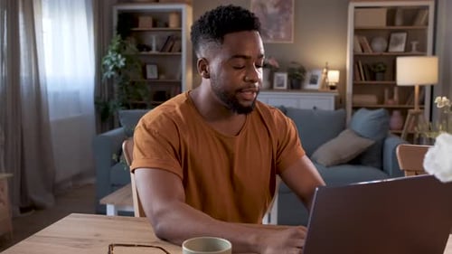 Young Adult Using Laptop at Table Indoors