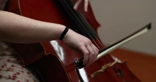 Young woman practicing playing the cello. Close-up straight ahead.