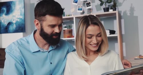 Couple Laughs Together Looking at Pictures at Home