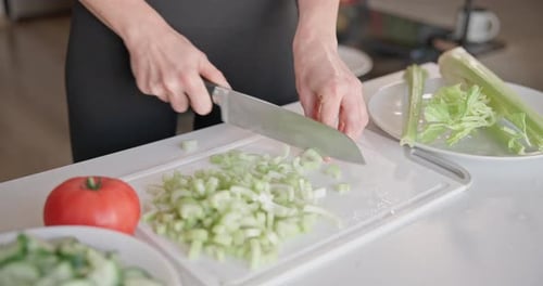 Home Cooking Woman in Small Apartment Cutting Fresh Organic Celery with Santoku Knife on Vegetable