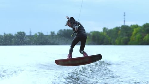 Male Wakeboarder Riding on River in Wakeboard. Sportsman Jumping High Above Water