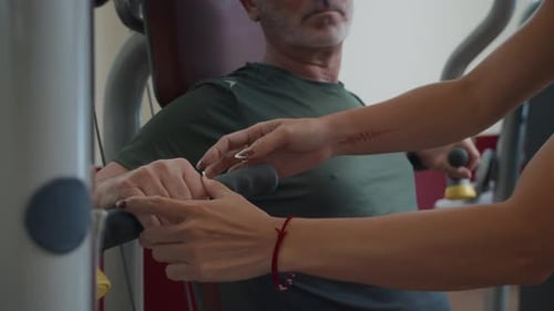 Coach Assisting Man Doing Chest Press Exercise on Machine