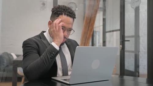 Tired Businessman Working at Laptop in Modern Office