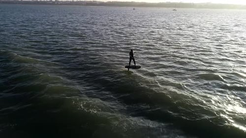 E Foil Sunset boating on the water. Paddleboard, stand-up surfing on electric foil. Aerial drone sho