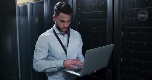 Young Man Working on Laptop in Server Room