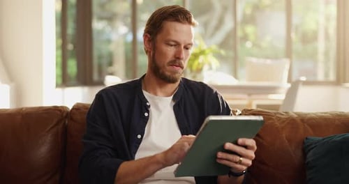 Man Using Tablet Device on Couch at Home