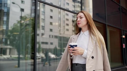 Woman Walks with Coffee Near Office Building