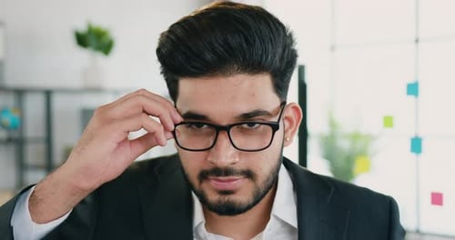 Attractive smiling business man office manager taking off his glasses while looking at camera