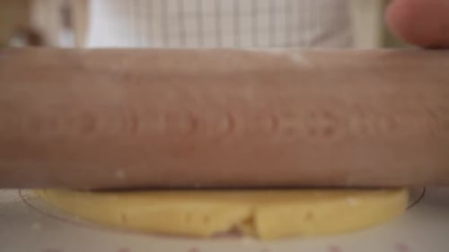 Close-up of a baker rolling out pastry dough towards camera.