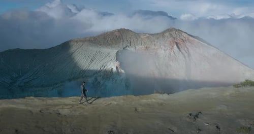 Man adventure hiking along cliff ridge at active volcano in East Java, profile shot, aerial