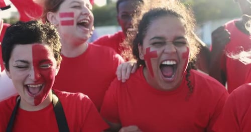 Excited Sports Fans Cheer with Painted Faces