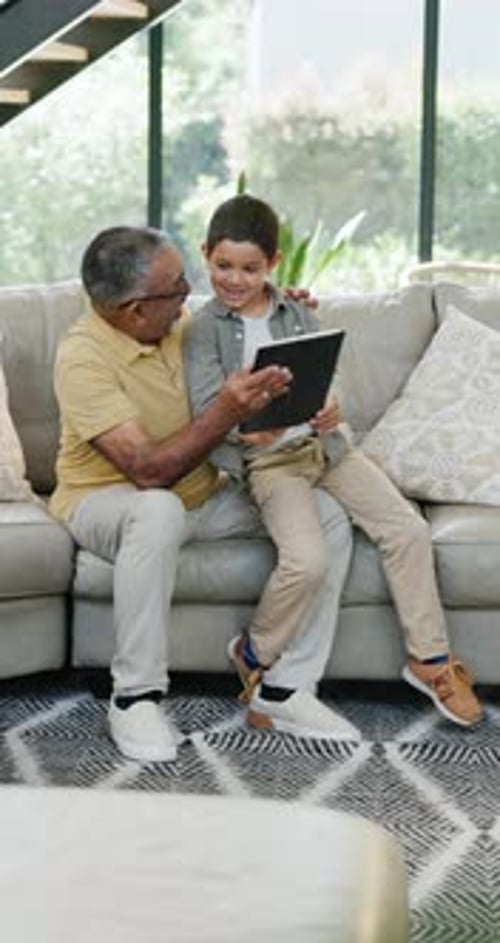 Grandfather and Child Using Tablet on Sofa