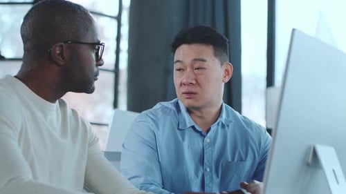 Two Adults Collaborating on Computer in Modern Workplace