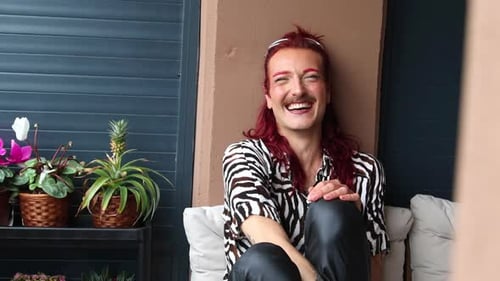 Non-binary person smiling and laughing on a balcony