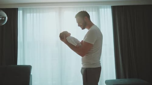 Proud Father Holds Newborn Baby Indoors