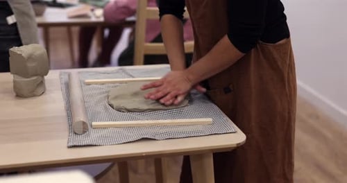 Hands Shaping Clay on a Table