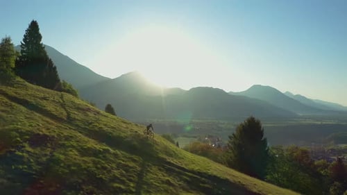 Amazing aerial view of man riding MTB E-bike down the empty trail. Nature paradise. Morning sun.