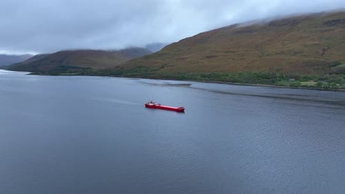 Cargo Ship Sailing Across Scenic Lake Surrounded by Mountains
