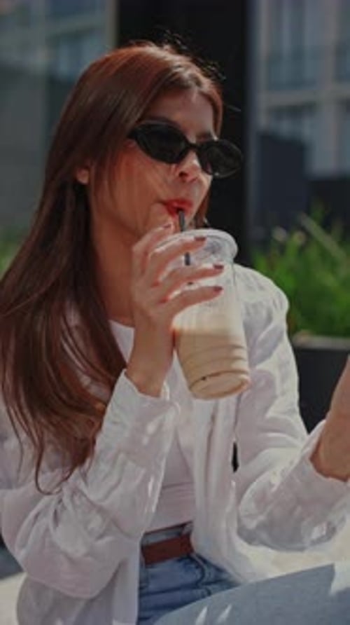 Stylish Woman Enjoying Iced Coffee in Urban Setting