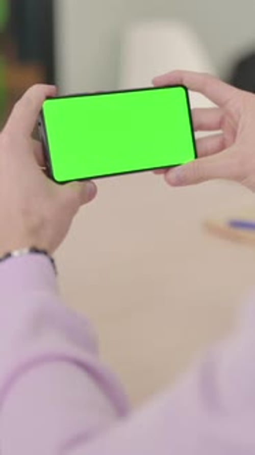 Rear View of Man Holding Smartphone with Green Screen, Vertical Video