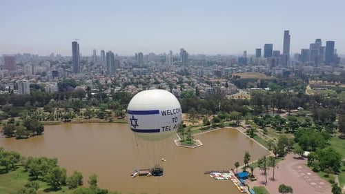 Aerial Shot Of Hot Air Balloon Descending Over Yarkon Park Against Sky In City