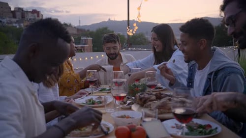Reunion of Diverse Happy Friends Eating and Drinking Sitting in a Table in a Rooftop Terrace